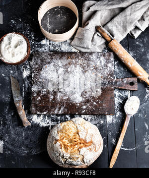 Gebackenes Brot, weißes Mehl von Weizen, Holz- Rolling Pin und alten Schneidbrett auf einem schwarzen Tabelle, Ansicht von oben Stockfoto