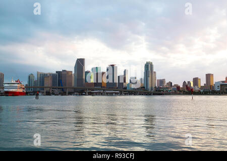 Miami Skyline der Stadt mit Brücke und Kreuzfahrtschiff bei Sonnenuntergang mit bewölktem Himmel. Urban Panorama von Miami City am Abend. Stockfoto