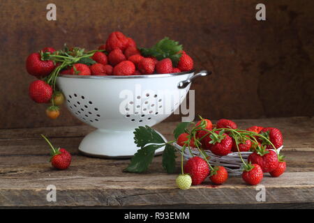 Reife Erdbeeren in einem Sieb auf einem Holztisch Stockfoto