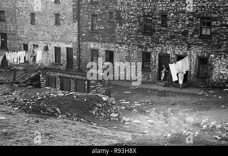 Mitte der 1940er Jahre, slum Gehäuse in Merthyr, South Wales, UK. Der Niedergang der lokalen Stahl und Kohle in den 1930er Jahren und dann wieder nach WW2 bedeutete Migration und Arbeitslosigkeit und große Armut und Not gelitten, mit schlechte Wohnverhältnisse und Lebensbedingungen. Hier sehen wir die lokalen Frauen setzen ihre Wäsche auf einer Wäscheleine außerhalb ihrer Häuser. Stockfoto