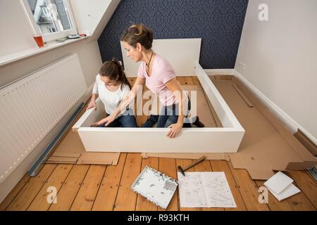 Mutter und Tochter gemeinsam ein Bett im Zimmer der Tochter zu montieren, Montage, Deutschland Stockfoto