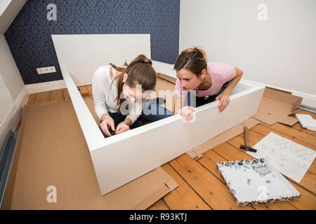Mutter und Tochter gemeinsam ein Bett im Zimmer der Tochter zu montieren, Montage, Deutschland Stockfoto