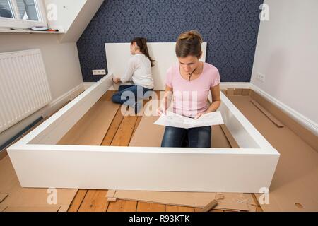 Mutter und Tochter gemeinsam ein Bett im Zimmer der Tochter zu montieren, Montage, Deutschland Stockfoto