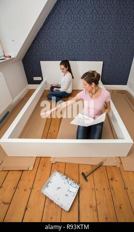 Mutter und Tochter gemeinsam ein Bett im Zimmer der Tochter zu montieren, Montage, Deutschland Stockfoto