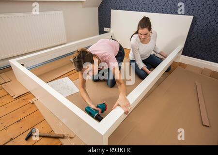 Mutter und Tochter gemeinsam ein Bett im Zimmer der Tochter zu montieren, Montage, Deutschland Stockfoto
