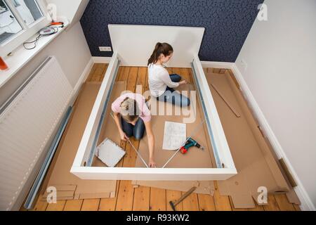 Mutter und Tochter gemeinsam ein Bett im Zimmer der Tochter zu montieren, Montage, Deutschland Stockfoto