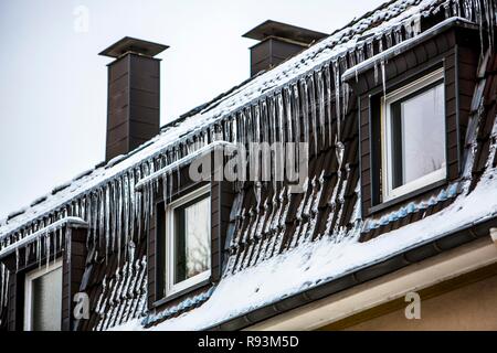 Große Eiszapfen hängen von der Traufe eines Hauses, Zeichen eines schlecht wärmegedämmten Dach, Essen, Nordrhein-Westfalen, Deutschland Stockfoto