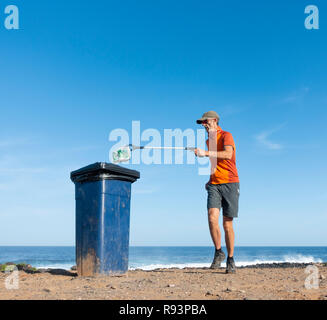 Ein Plogger/Jogger sammelt Plastikmüll am Strand während seines morgendlichen Lauf Stockfoto