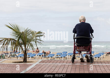 Älterer Mann siiting auf Wanderer mit Blick über Strand in Spanien. Stockfoto
