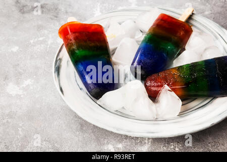 Rainbow bunte Eis Popsicle mit Holz stick in Marmor Platte auf grauem Hintergrund. Fertig zu werden. Essen Hintergrund Stockfoto
