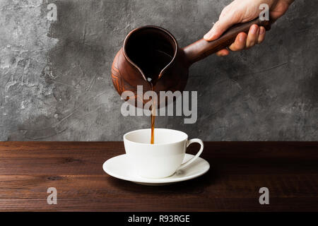Kaffee in weiße Tasse und Lehm cezve auf hölzernen Hintergrund Stockfoto