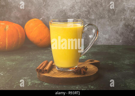 Kürbis Latte mit Gewürzen (Zimt, Anis) auf einem grünen Hintergrund. Getönt Stockfoto