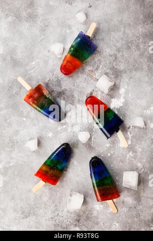 Rainbow Speiseeis popsicle auf grauem Hintergrund. Ansicht von oben. Essen Hintergrund Stockfoto
