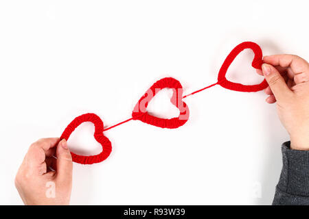 Red handmade diy Herzen aus Karton, Garn auf einem weißen Hintergrund. Geschenkideen für Valentinstag, Tag Liebe, Konzept der 14. Februar. Schritt für Schritt. Stockfoto