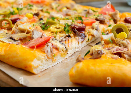 Leckere Pizza mit Pilzen, Huhn, Peperoni, Oliven, Mais in Stücke schneiden. Nahaufnahme Stockfoto