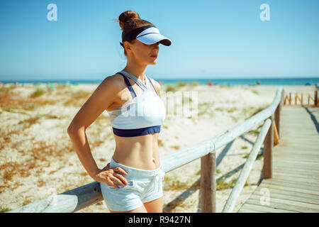 Gesunde Frau Jogger in Fitness Kleidung auf das Meer in die Ferne schauen. fir Frau entspannend nach dem Joggen und die schöne Natur genießen. Stockfoto