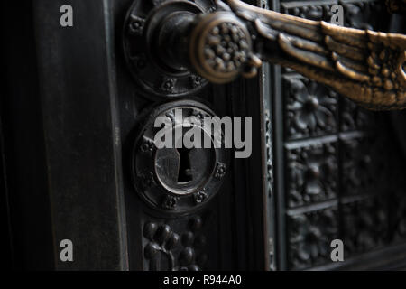 Schlüsselloch einer alten Kirche Tür sieht in dieser Nahaufnahme. Die schwarze hölzerne Architektur und goldenen Messing griff fabelhaft aussehen. Stockfoto