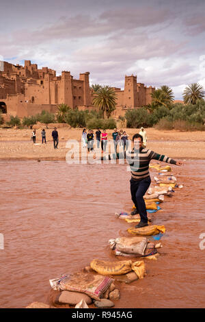 Marokko, Ouarzazate, Ksar Ait-Ben-Haddou, Kasbah, Mann mit ounila Fluss Stepping Stones Stockfoto