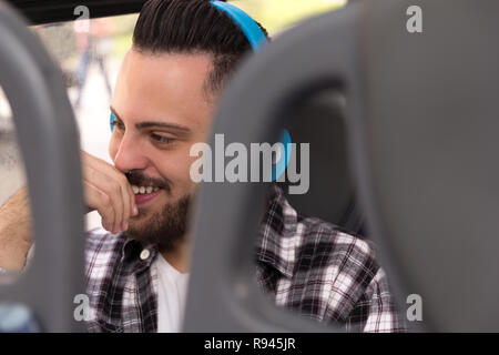 Konzept der Pendeln, urbanes Leben, Hoffnungen, die Fahrt. Glückliche junge Reisende tragen Plaid Shirt Hören von Musik in der Stadt mit dem Bus. Stockfoto