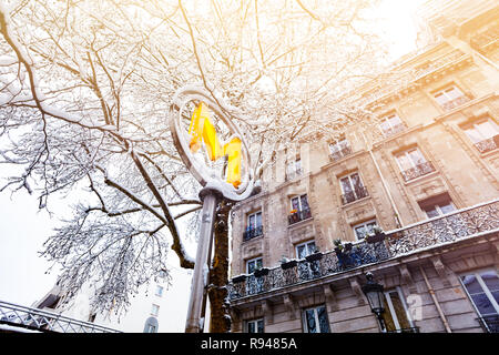 Low Angle View der Metro Zeichen gegen Bäume und Gebäude mit Schnee bedeckt in Paris Stockfoto