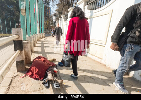 Fußgänger auf einem Kathmandu Straße vorbei an einem Ausgestreckten behinderte Bettler Leiden vom Aussatz, Nepal, Asien Stockfoto