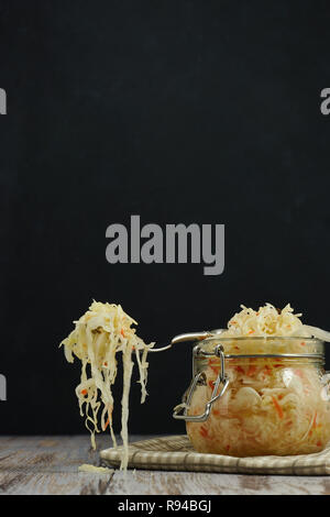 Ein Glas von Sauerkraut und Karotten im eigenen Saft mit Gewürzen auf leichte, weiße Holztisch, ein vertikaler Art von Kohl in einem jar. traditionellen Home-m Stockfoto