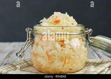 Ein Glas von Sauerkraut und Karotten im eigenen Saft mit Gewürzen auf leichte, weiße Holztisch, ein vertikaler Art von Kohl in einem jar. traditionellen Home-m Stockfoto