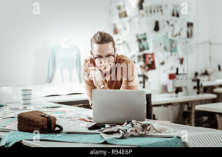 Die jungen langhaarigen Designer von einem Mode Schule arbeitet an einem neuen Konzept Stockfoto