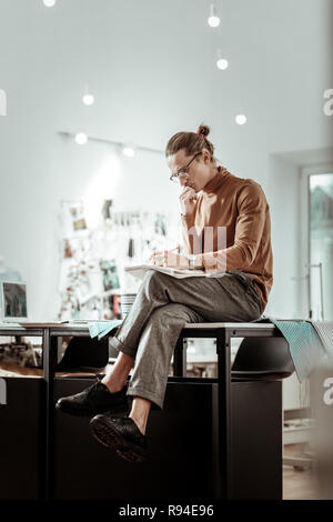 Hübscher junger Designer aus Modeschule in schwarze Schuhe konzentriert Stockfoto