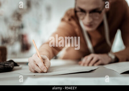 Professionelle Designer aus einer Modeschule mit einer Uhr auf seiner Hand arbeiten hart Stockfoto