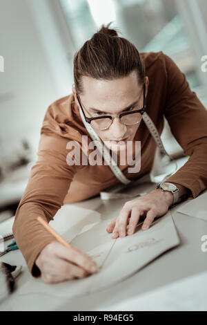 Professionelle Designer aus einer Modeschule mit langen Haaren die benötigten Messungen Stockfoto
