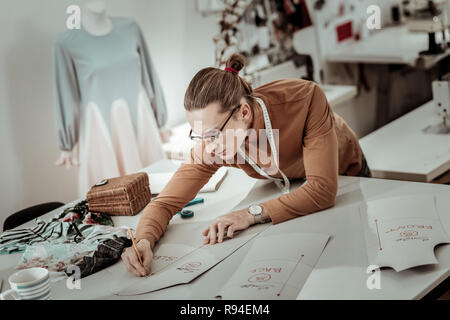 Junge Designer Brillen mit langen Haaren arbeitet an einem neuen Kleid Modell Stockfoto