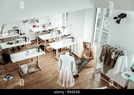 Hübscher junger Modedesigner mit langen Haaren im neuen Kleid suchen Stockfoto