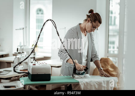 Young Fashion Designer von Generation Y mit langen Haaren auf der Suche konzentriert Stockfoto