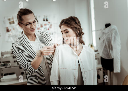 Strahlende Dunkelhaarige mit hellen Make-up Arbeiten mit einem trendigen Designer Stockfoto