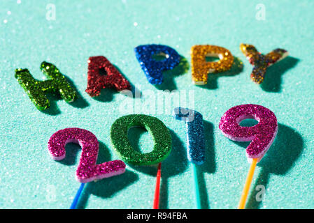 Nahaufnahme von einigen glitter Buchstaben und Zahlen in verschiedenen Farben, die den Text gerne 2019, auf einem blauen Glitzer Hintergrund Stockfoto