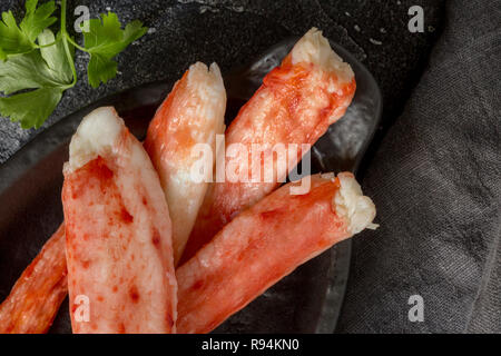 Close up Crab Sticks Luxury King auf schwarze Platte mit Petersilie auf schwarzen Hintergrund. Urlaub Gericht Stockfoto