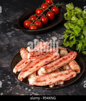 Luxury Kamtschatka Crab Sticks auf schwarze Platte mit Petersilie und Kirschtomaten auf schwarzen Hintergrund. Urlaub Gericht Stockfoto