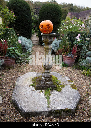 Halloween in Chenies Manor. Geschnitzten Kürbis auf der Sonnenuhr im Garten Weg durch den Torbogen gehen Ende Oktober. Hochformat. Stockfoto