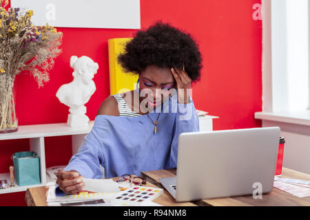 Hart arbeitende Künstler mit starken Kopfschmerzen und Müdigkeit Stockfoto