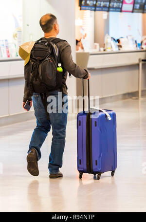 TOKYO, JAPAN - 7 November, 2017: Ein Mann mit einem blauen Koffer am Flughafen. Ansicht von hinten. Mit selektiven Fokus Stockfoto