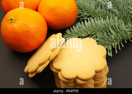 Ingwer cookies, Tannenzweigen und Tangerinen, auf einem dunklen Hintergrund, Nahaufnahme Stockfoto
