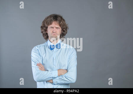 Nachtragend Mann mit Armen über grauer Hintergrund im Studio Schoß gefaltet und beleidigt von der Kamera sah. Verärgert Kerl sehr zornig und gehen Sie zu weinen. Stockfoto