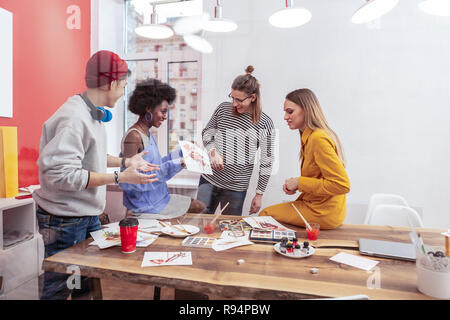 Fröhliche afroamerikanischen Studenten ihre Arbeiten zeigen, groupmates Stockfoto