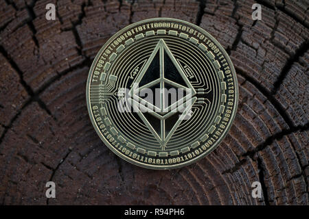 Des astraleums Classic cryptocurrency physischen Münze auf den alter Baumstumpf gelegt. Makroaufnahme. Stockfoto