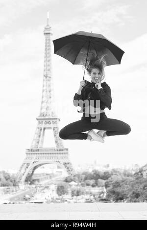 Träume werden wahr. Lady touristische Sportlich und aktiv in das Stadtzentrum von Paris springt auf. Mädchen touristische genießen und Sightseeing. Dame mit Schirm über den Besuch Eiffelturm aufgeregt, Himmel Hintergrund. Stockfoto