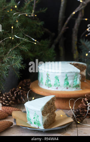 Festliche Kuchen mit gemalten Weihnachtsbaum auf einem dunklen Hintergrund der Zweige und Zapfen dekoriert. Rustikaler Stil, selektiven Fokus. Stockfoto