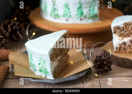 Festliche Kuchen mit gemalten Weihnachtsbaum auf einem dunklen Hintergrund der Zweige und Zapfen dekoriert. Rustikaler Stil, selektiven Fokus. Stockfoto