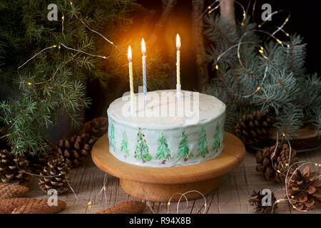 Festliche Kuchen mit gemalten Weihnachtsbaum auf einem dunklen Hintergrund der Zweige und Zapfen dekoriert. Rustikaler Stil, selektiven Fokus. Stockfoto