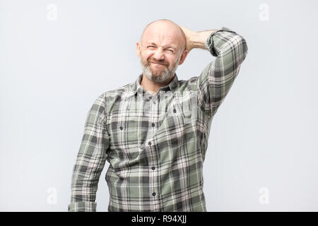 Elend und düsteren Kerl, runzelte die Stirn und Suchen unzufrieden, während Kratzen Kopf Stockfoto